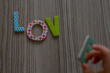 Child is Writing Word Love From Colourful Toy Letters