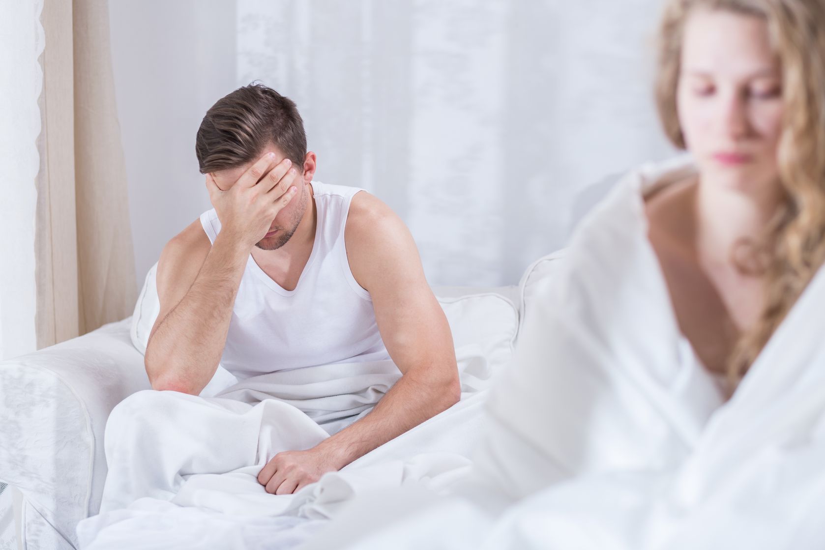 Man and woman sitting unhappy in bed