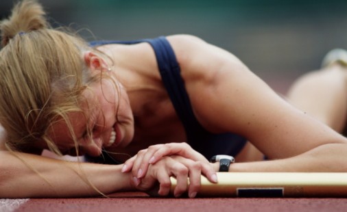 woman lying on athletic track in pain