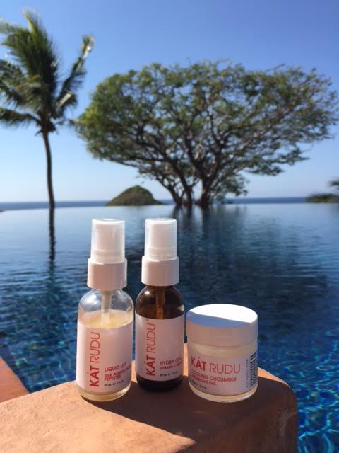 Kat Rudu Beauty Collection -- image of bottles against a backdrop of sky, pool, and trees