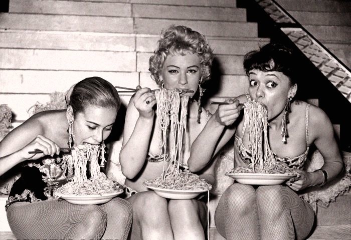 three women eating lots of spaghetti