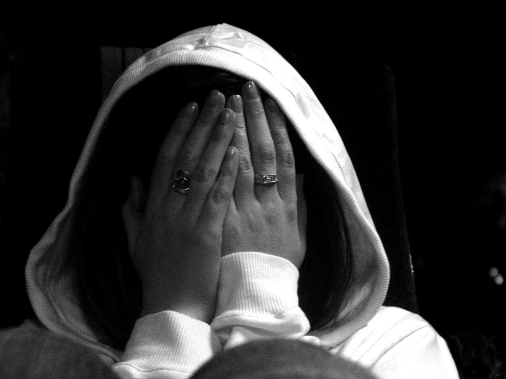 woman covering face with hands in anguish
