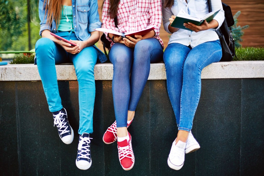three teen girls reading outside