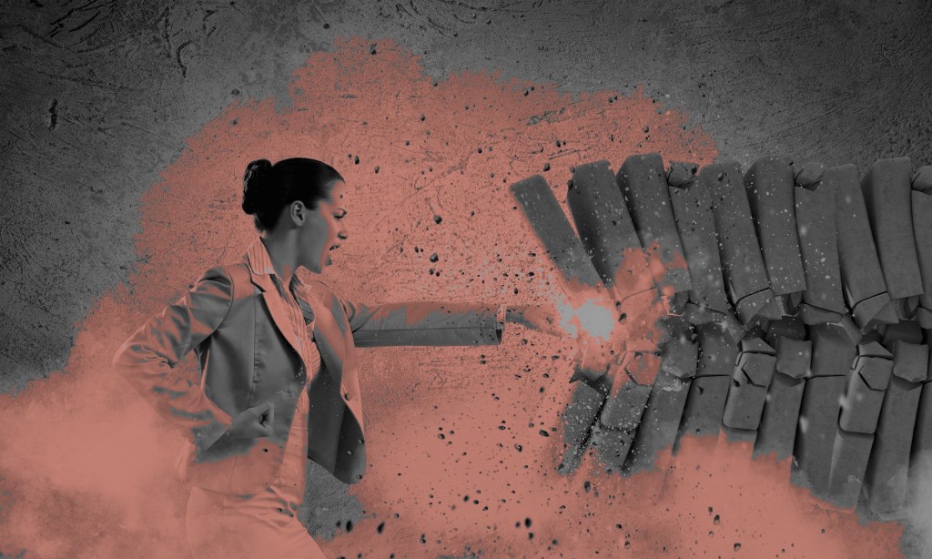 Image of businesswoman breaking bricks with hand-Edit