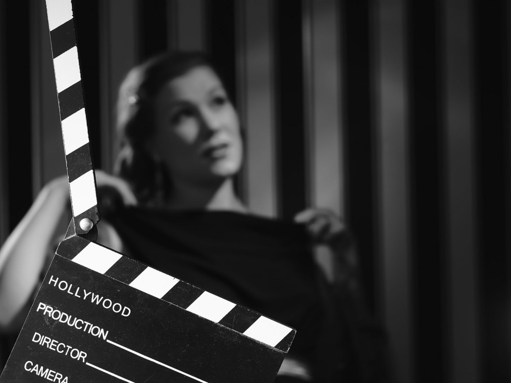 black and white, a beautiful acting woman and a clapboard - minimal lighting and strong contrast