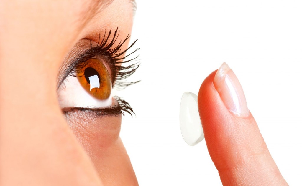 Closeup of a woman inserting a contact lens in her eye