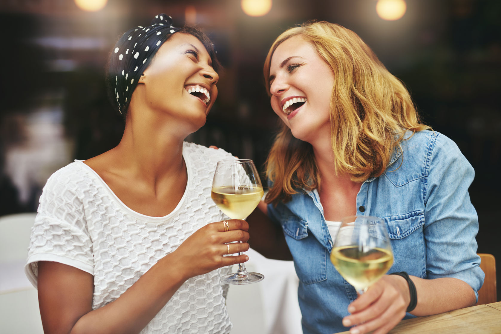 46626161 - two young attractive vivacious multiethnic female friends celebrating and laughing together over a glass of white wine