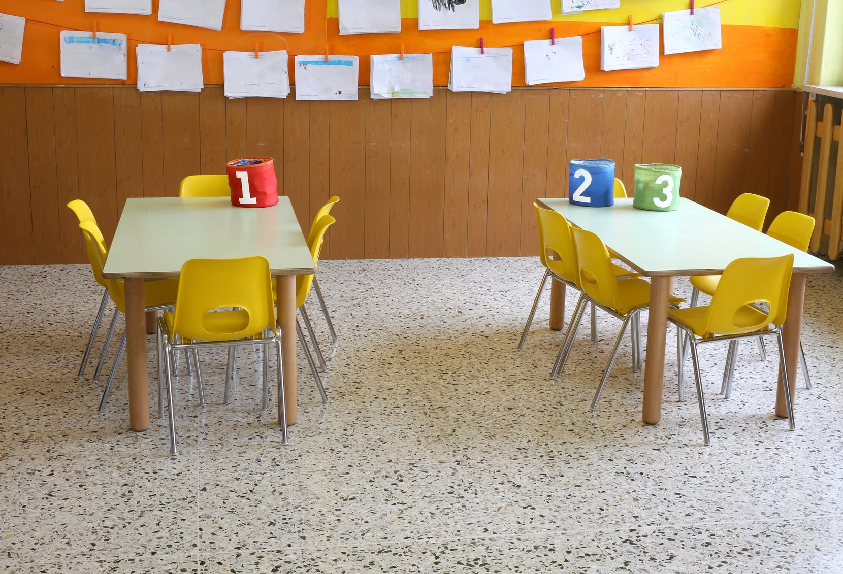 56045682 - kindergarten classroom with the yellow chairs and many children's drawings on the walls