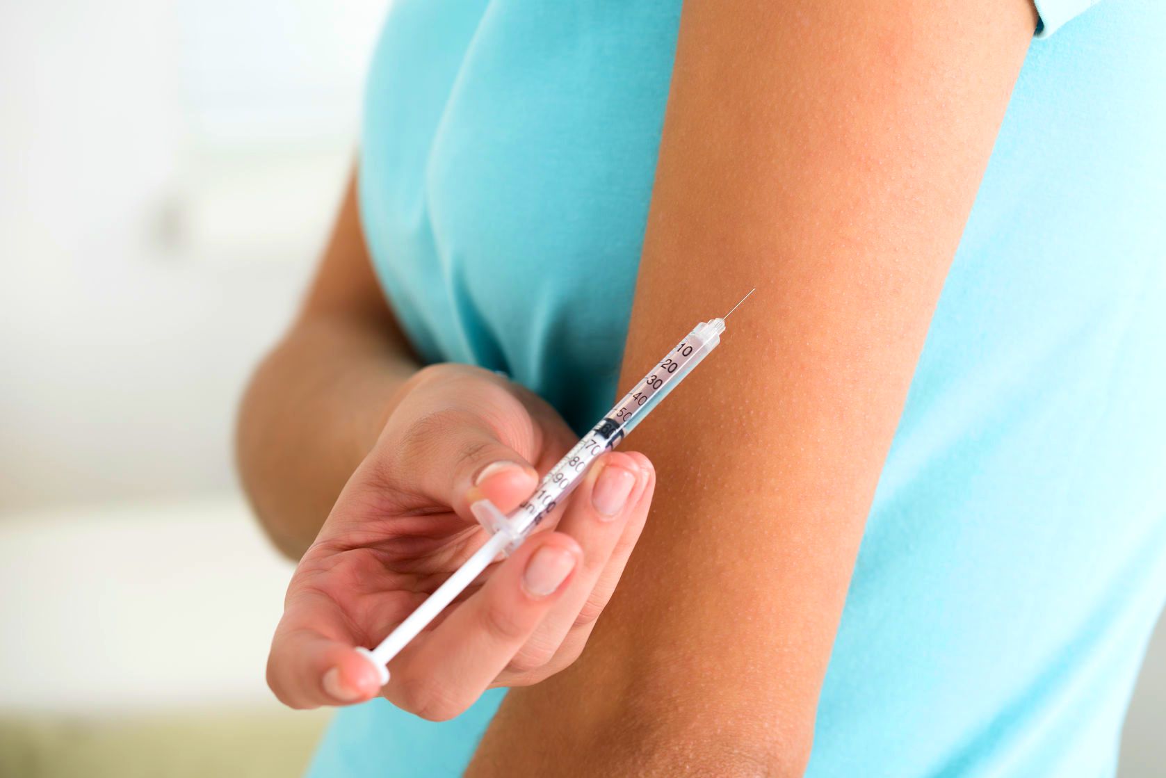 woman injecting herself in the arm with hormones